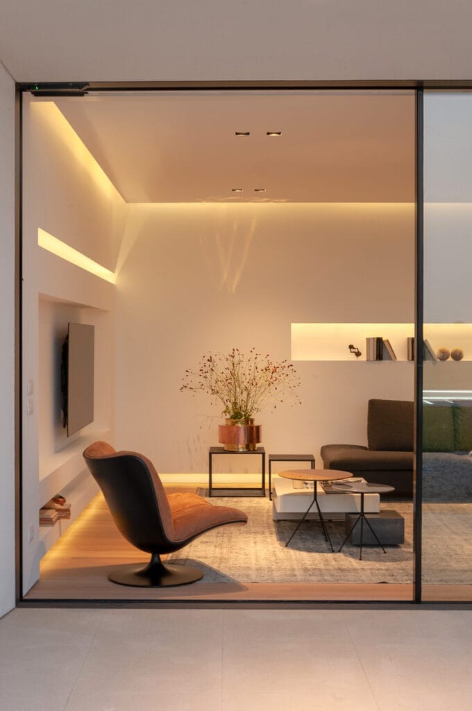 Design d'interni moderno di Villa MD Home a Verona, con vista sull'open space illuminato, caratterizzato da una poltrona di design, tavolini e un'ampia vetrata che connette l'interno con l'esterno