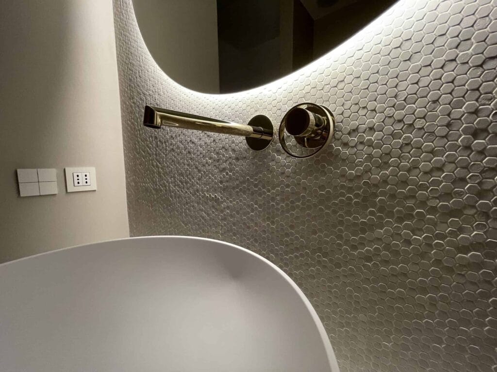 Interni ville di lusso 10 Dettaglio di parete in pietra con rubinetteria a parete in ottone, bagno di AV Home