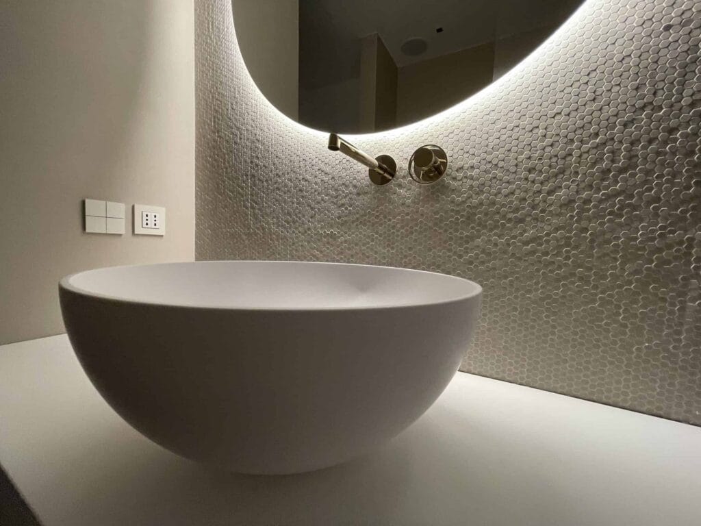 Interni ville di lusso 6 Lavabo a bacinella con specchio tondo retroilluminato e parete materica, interni ville di lusso